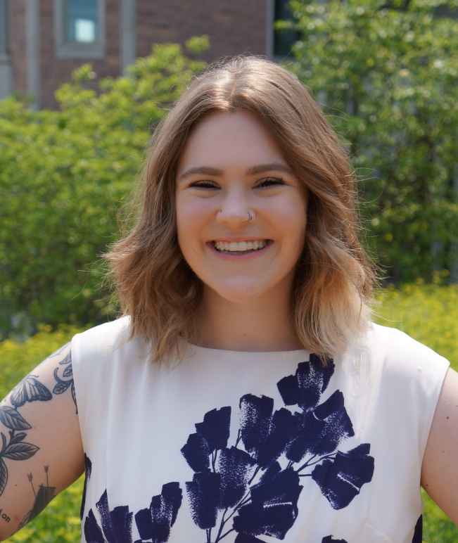 A woman with light skin wearing a floral shirt with shoulder length hair