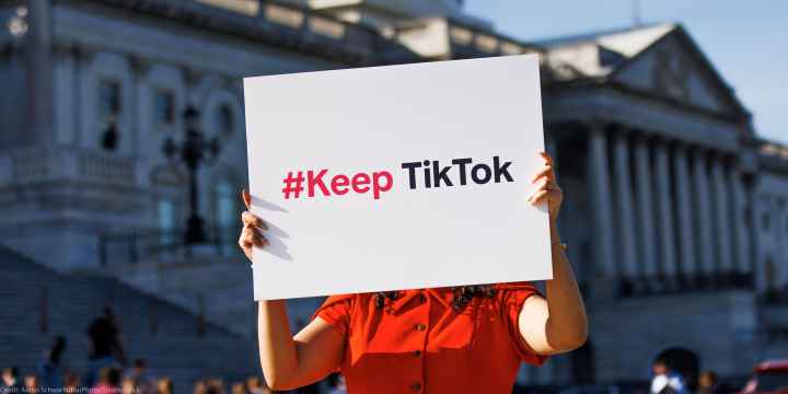 A person is holding a sign outside the Capitol Building that reads " #Keep TikTok".