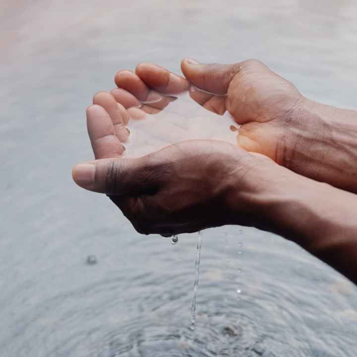 Two hands holding water, creating ripples on the surface below.