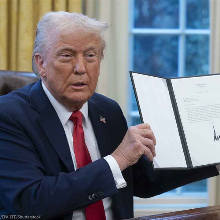 President Donald Trump holds up a recently signed executive order in the Oval Office of the White House.